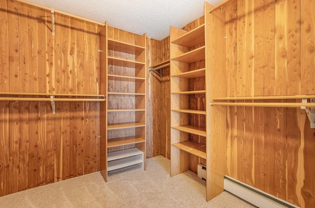 spacious closet with a baseboard radiator and light colored carpet