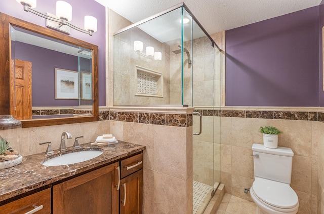 bathroom with tile walls, an enclosed shower, vanity, a textured ceiling, and toilet