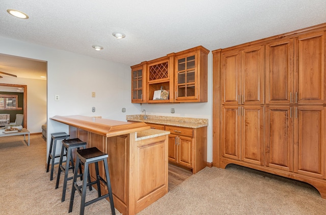 kitchen featuring a kitchen breakfast bar, a center island, carpet floors, and a textured ceiling