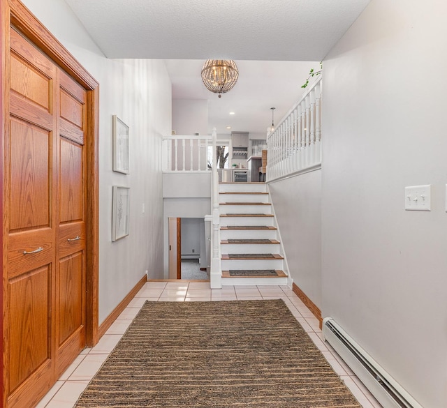 staircase with a notable chandelier, tile patterned flooring, and a baseboard heating unit