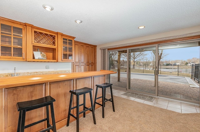 kitchen with light tile patterned flooring, a textured ceiling, a breakfast bar area, and a wealth of natural light