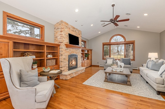 living room featuring vaulted ceiling, a fireplace, light hardwood / wood-style floors, and a baseboard heating unit