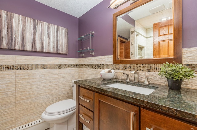 bathroom featuring baseboard heating, tile walls, vanity, a textured ceiling, and toilet