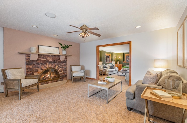 carpeted living room featuring ceiling fan, a stone fireplace, and a textured ceiling