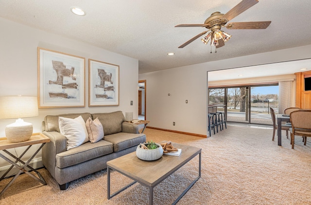 living room with light carpet, ceiling fan, and a textured ceiling