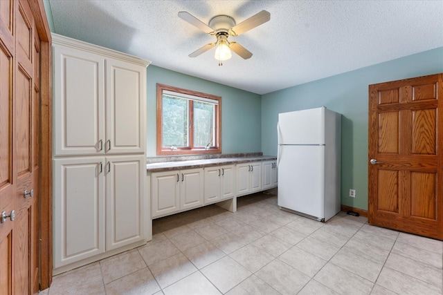 kitchen with light tile patterned flooring, a textured ceiling, white refrigerator, ceiling fan, and white cabinets