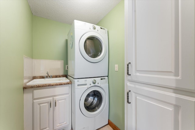 washroom with cabinets, stacked washer / dryer, sink, and a textured ceiling