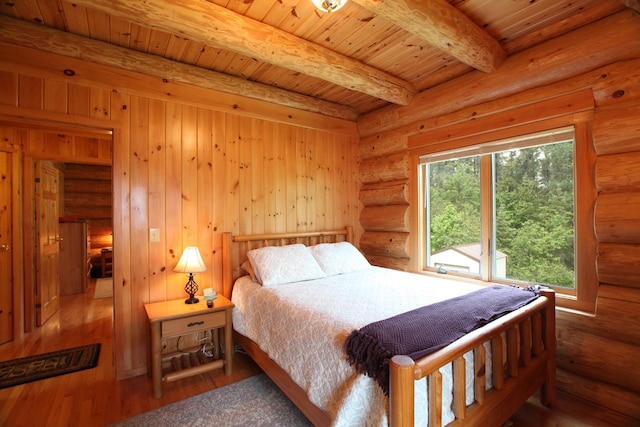 bedroom with beamed ceiling, log walls, dark hardwood / wood-style floors, and wooden ceiling