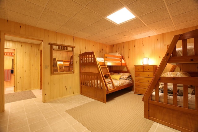 tiled bedroom featuring a drop ceiling and wooden walls