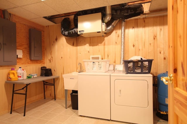 laundry area with wooden walls, washing machine and clothes dryer, and light tile flooring