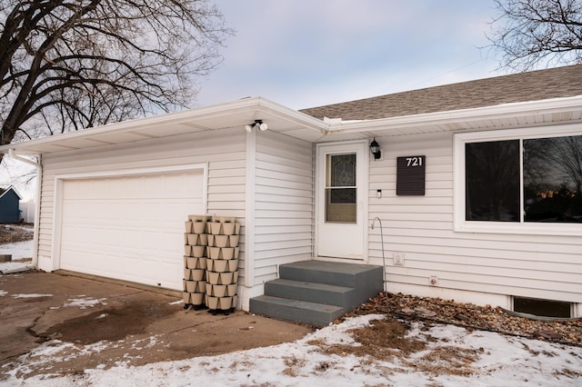 snow covered property entrance featuring a garage