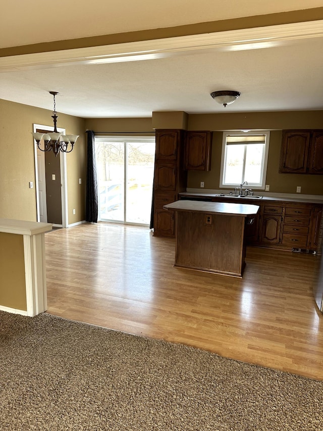 kitchen featuring dark brown cabinets, decorative light fixtures, a kitchen island, light hardwood / wood-style floors, and a chandelier