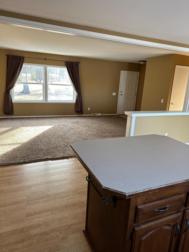 kitchen featuring a kitchen island, dark brown cabinets, and light carpet