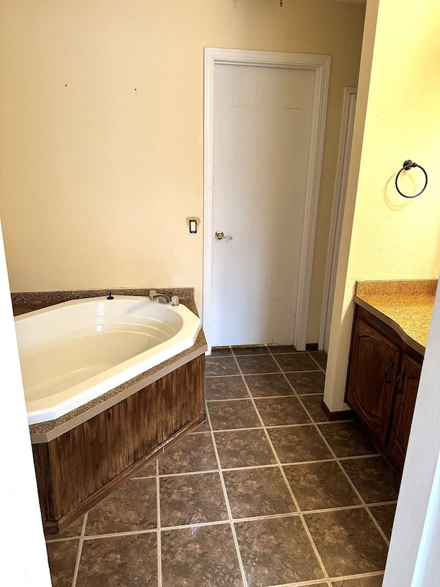 bathroom with a washtub, vanity, and tile floors