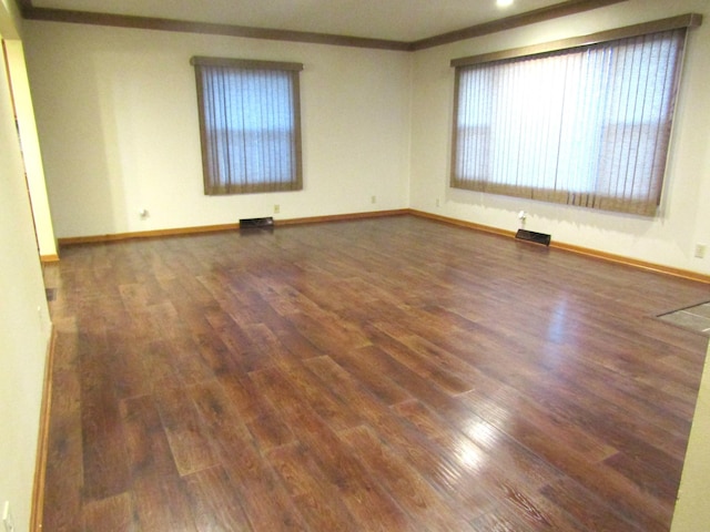 spare room featuring dark hardwood / wood-style floors and crown molding