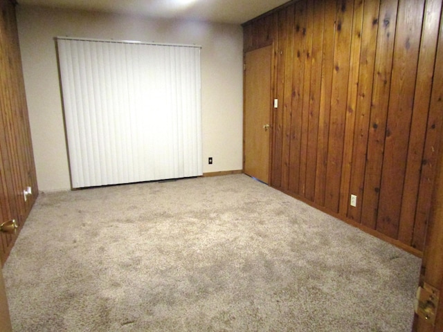 empty room featuring light colored carpet and wooden walls