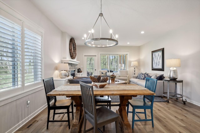 dining space featuring an inviting chandelier, light wood-type flooring, and a fireplace