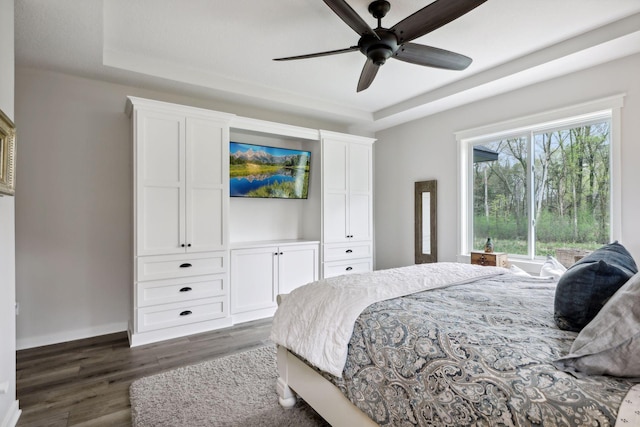 bedroom featuring a tray ceiling, dark hardwood / wood-style flooring, and ceiling fan