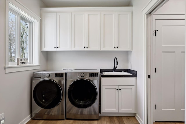 washroom with a wealth of natural light, cabinets, washer and clothes dryer, and light hardwood / wood-style floors