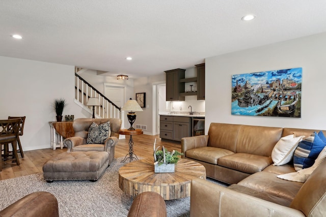 living room with beverage cooler, hardwood / wood-style floors, and sink