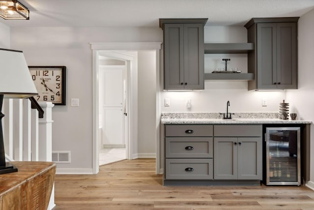 kitchen with beverage cooler, gray cabinetry, and light hardwood / wood-style flooring