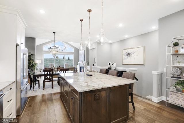 kitchen with stainless steel fridge, a kitchen breakfast bar, lofted ceiling, dark wood-type flooring, and a chandelier