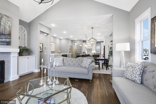 living room with an inviting chandelier, high vaulted ceiling, and dark hardwood / wood-style flooring