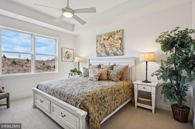 carpeted bedroom with ceiling fan and a tray ceiling