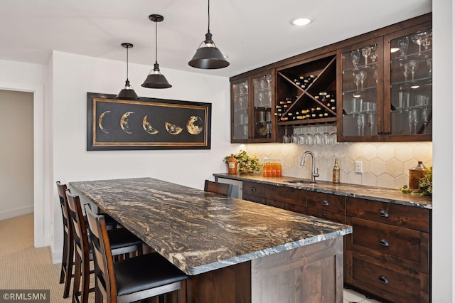 bar featuring dark brown cabinetry, sink, and dark stone counters