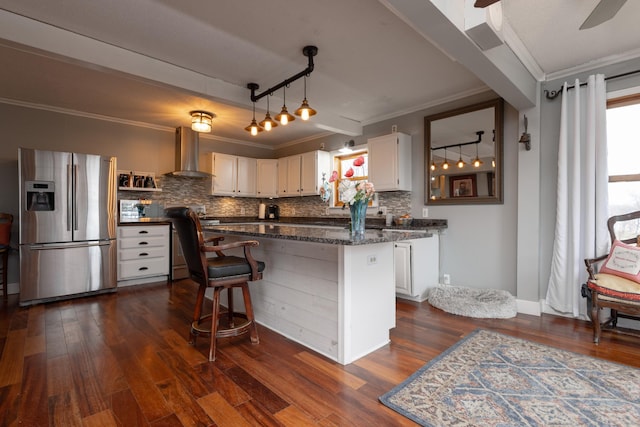 kitchen featuring stainless steel appliances, wall chimney range hood, tasteful backsplash, dark stone counters, and white cabinets