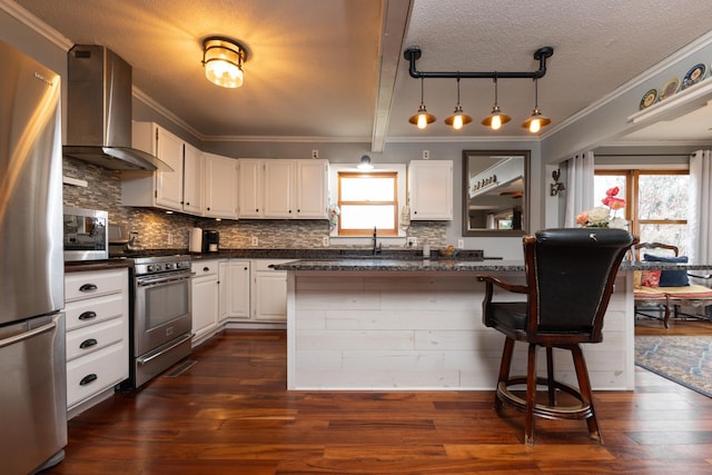 kitchen with a breakfast bar, white cabinets, wall chimney range hood, tasteful backsplash, and stainless steel appliances