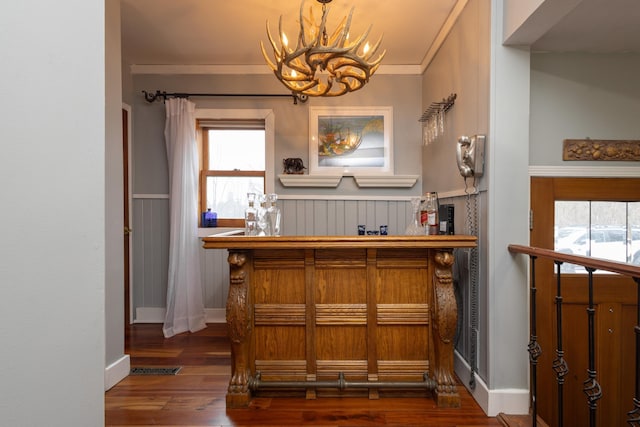 bar featuring crown molding, dark hardwood / wood-style flooring, and an inviting chandelier