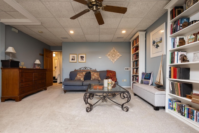 living room featuring a paneled ceiling, light colored carpet, and ceiling fan