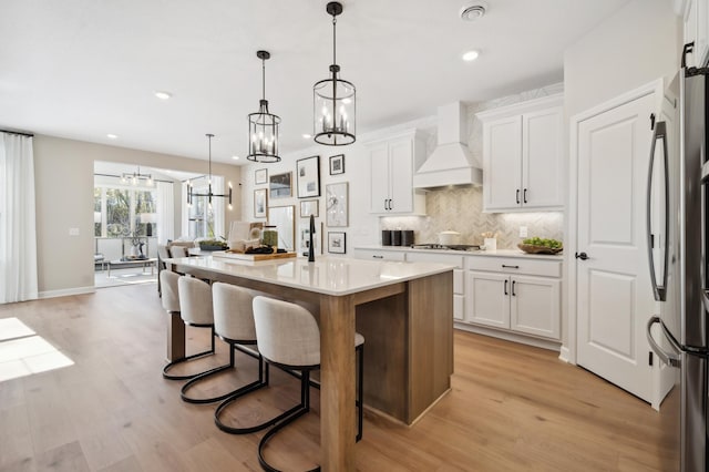 kitchen with premium range hood, pendant lighting, a chandelier, and white cabinetry