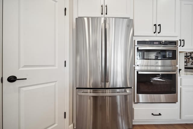 kitchen featuring hardwood / wood-style flooring, appliances with stainless steel finishes, and white cabinetry