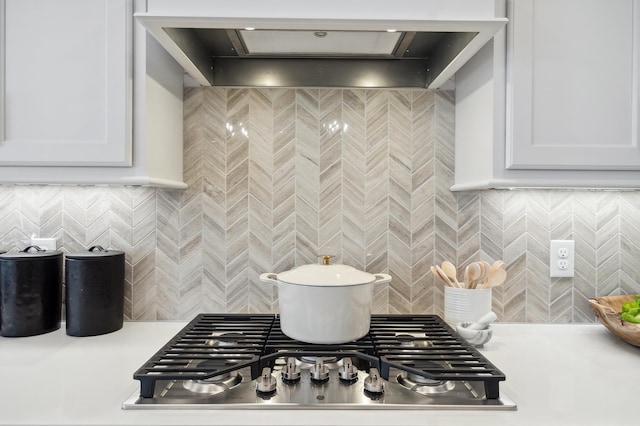 kitchen with tasteful backsplash, stainless steel gas stovetop, and white cabinets