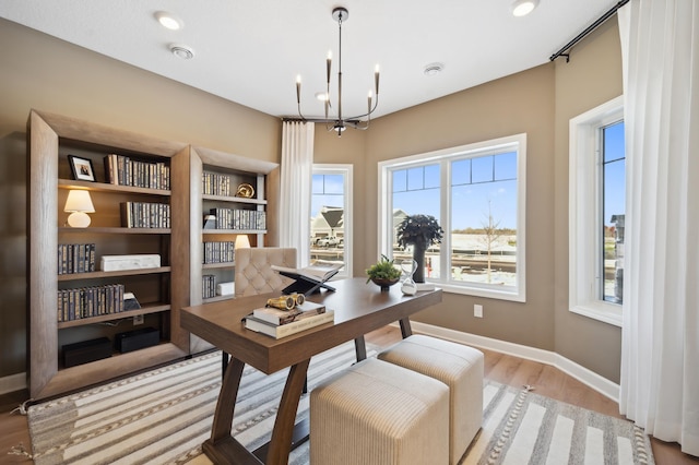 home office with a notable chandelier, light hardwood / wood-style floors, and a wealth of natural light