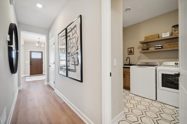 interior space with sink, light hardwood / wood-style floors, a chandelier, and washing machine and dryer