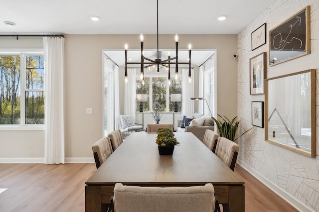 dining area with light hardwood / wood-style flooring and a notable chandelier