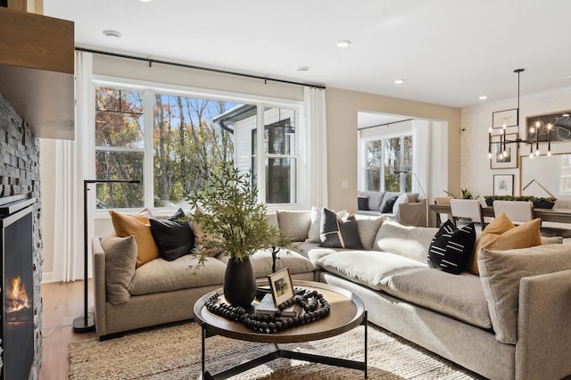 living room featuring light hardwood / wood-style flooring, a fireplace, and an inviting chandelier