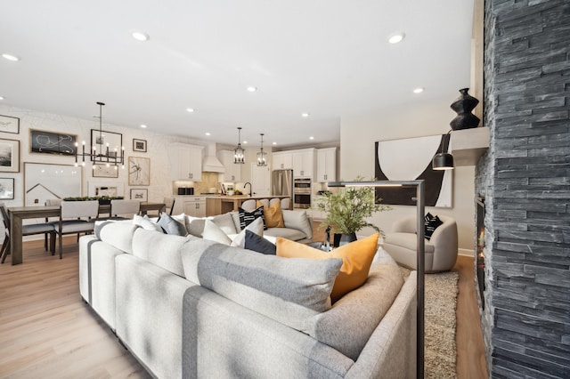 living room featuring a chandelier, light hardwood / wood-style floors, and sink