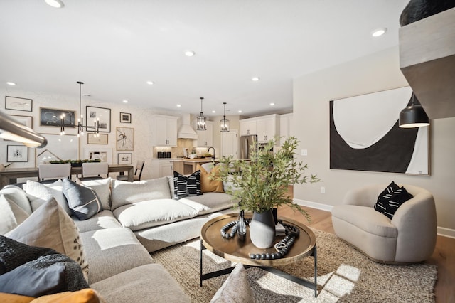 living room with sink, light hardwood / wood-style floors, and a chandelier