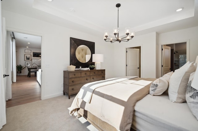 carpeted bedroom featuring an inviting chandelier and a tray ceiling