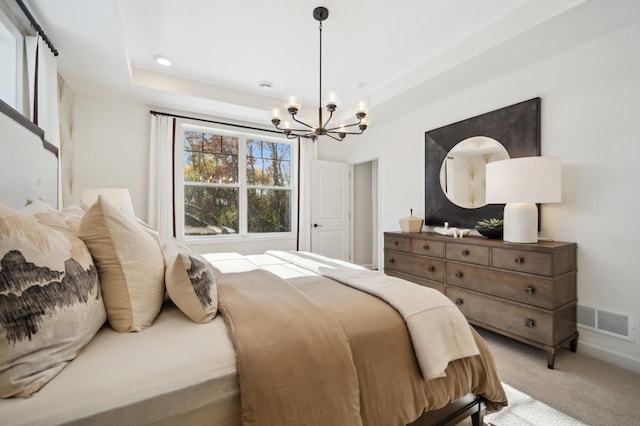 bedroom with light colored carpet, a notable chandelier, and a tray ceiling