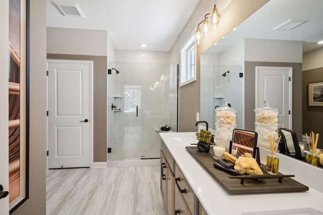 bathroom with wood-type flooring, dual vanity, and a shower with door