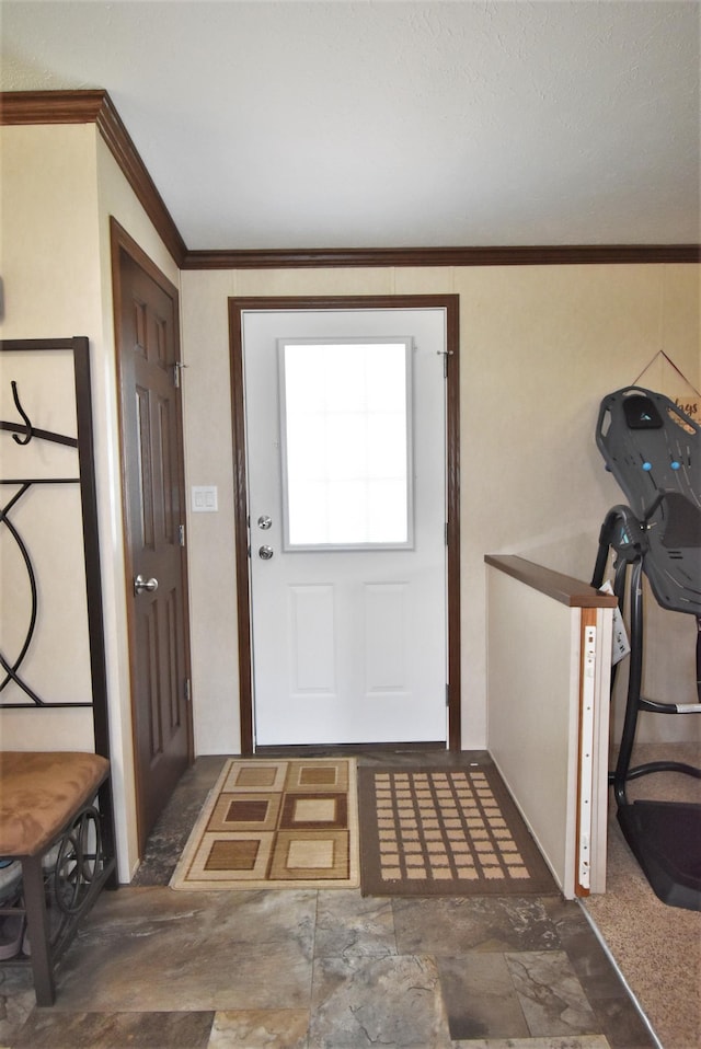 doorway to outside with dark tile floors and ornamental molding