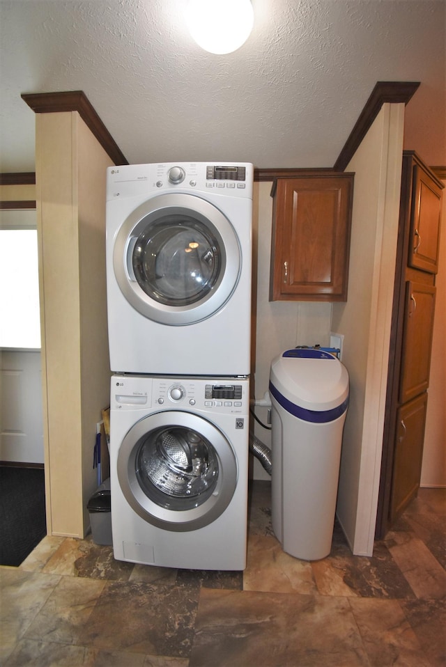 laundry room with a textured ceiling and stacked washer / dryer