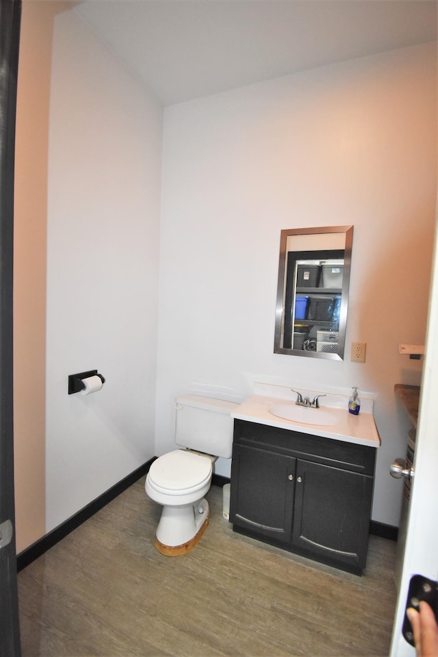 bathroom with hardwood / wood-style flooring, toilet, and vanity