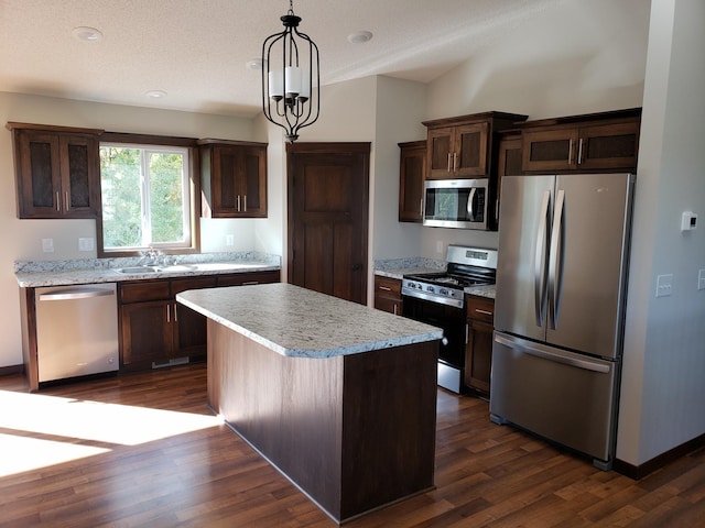 kitchen with a kitchen island, appliances with stainless steel finishes, dark hardwood / wood-style flooring, and decorative light fixtures