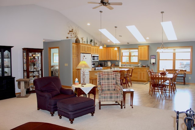 living room featuring light carpet, high vaulted ceiling, sink, a skylight, and ceiling fan